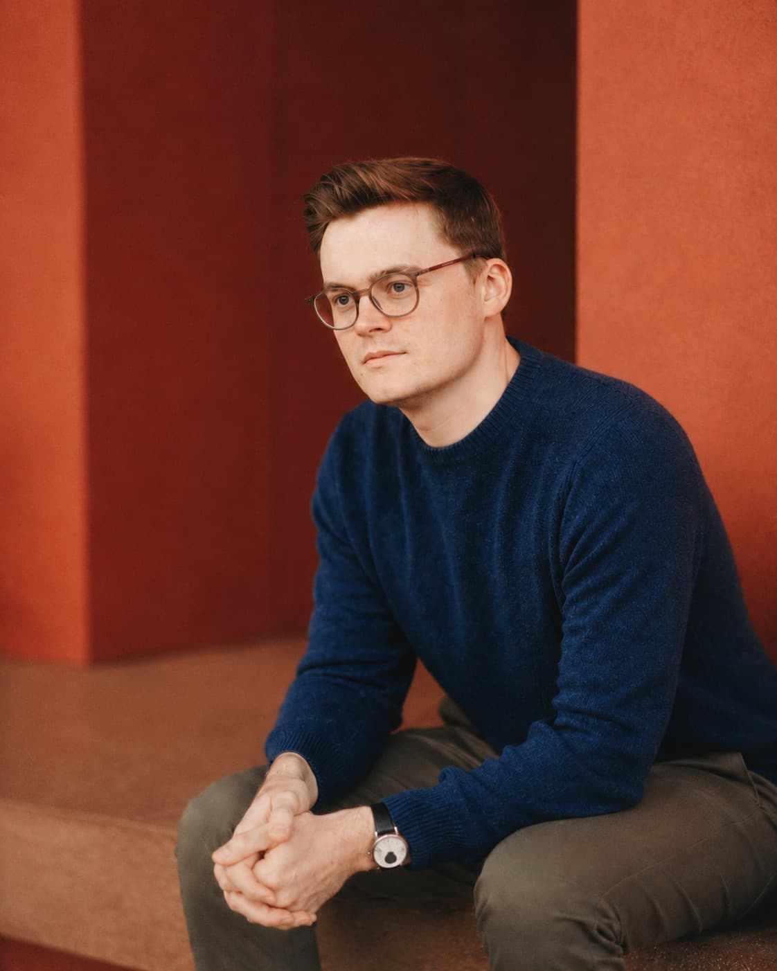 Dan McKenzie seated against a terracotta wall
